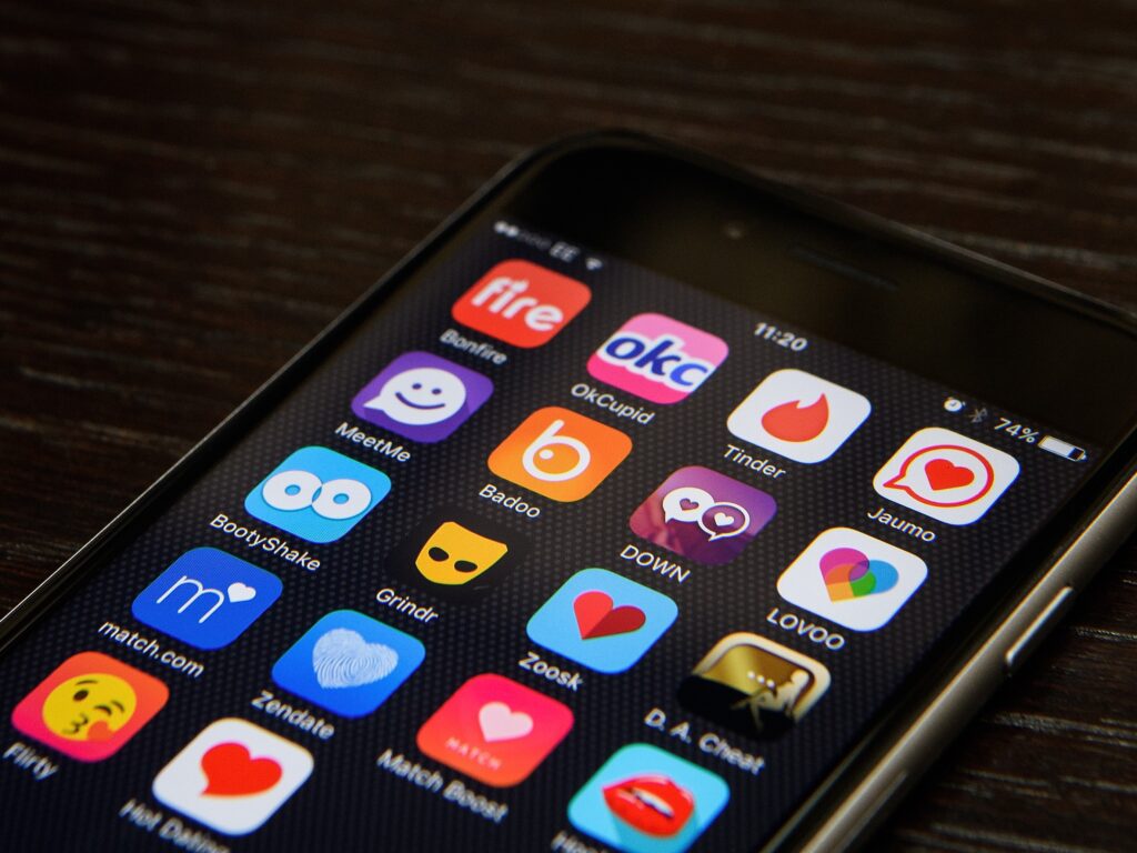 A smartphone screen displaying a grid of various dating apps including Tinder, Bumble, Badoo, and Zoosk, representing the shift toward using these platforms for a modern job search